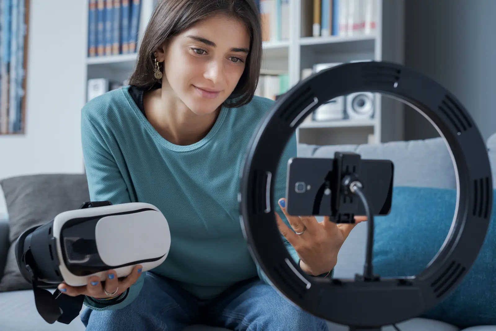 Young woman holding a VR headset in front of a phone-mounted ring light